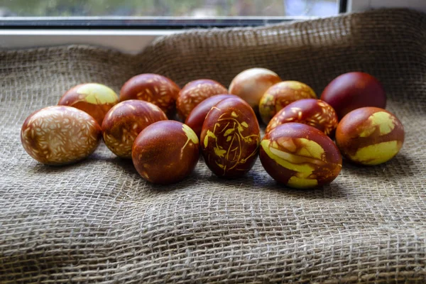 Huevos de pollo coloreados con método natural anticuado por cáscaras de cebolla. Huevos marrones con diferentes patrones naturales en la arpillera beige. Enfoque selectivo con copyspace. Concepto tradicional de Pascua y Primavera — Foto de Stock