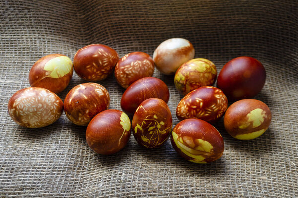 Chicken eggs colored with old-fashioned natural method by onion husks. Brown eggs with different natural patterns on beige burlap. Selective focus with copyspace. Traditional Easter and Spring concept