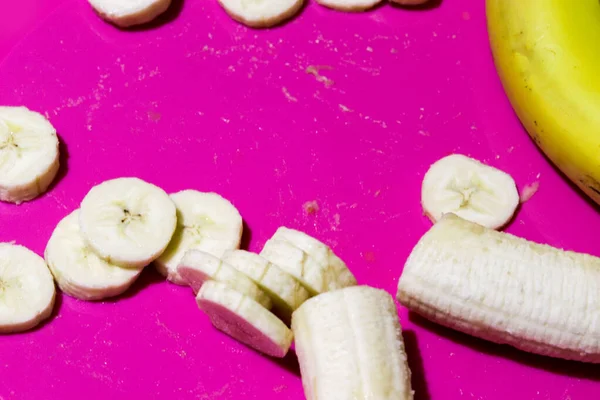 Plastry banana widok z góry na różowym lub fioletowym tle. Skopiuj miejsce na tekst. Zdrowe odżywianie i zdrowy tryb życia — Zdjęcie stockowe
