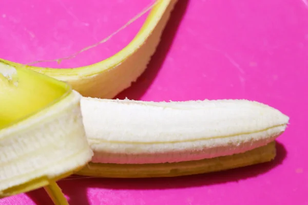 Otwarty banan z bliska widok z góry na różowy lub fioletowy tle z miejsca na tekst na temat zdrowia, żywienia lub podróży — Zdjęcie stockowe
