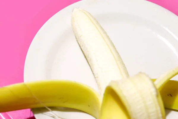 Otwarty banan na talerzu na różowym tle z przestrzenią do kopiowania — Zdjęcie stockowe