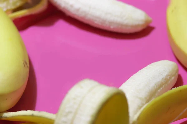 Kilka otwartych bananów zamyka widok z góry na różowym tle. Owoce tropikalne — Zdjęcie stockowe
