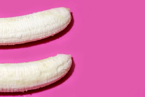 Dwa obrane banany na różowym tle widok z góry zbliżenie. Leżał płaski z kopią miejsca na tekst — Zdjęcie stockowe