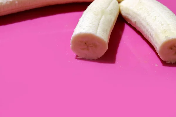 Hakket banan på pink skrivebord. Close up på lilla baggrund med kopiplads - Stock-foto