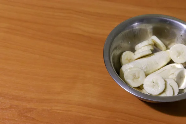 Μπανάνα φέτες σε ένα μεταλλικό πιάτο σε ένα ξύλινο τραπέζι με χώρο αντίγραφο. Κάτοψη των τροπικών φρούτων και της υγιεινής διατροφής — Φωτογραφία Αρχείου