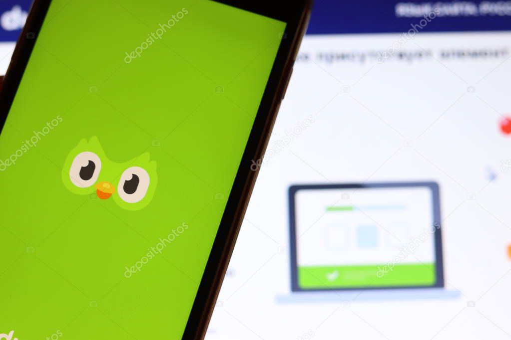 Mobile phone with Duolingo icon on screen close up with website on laptop. Blurred background with duolingo  logo. Los Angeles, California, USA - 9 November 2019, Illustrative Editorial