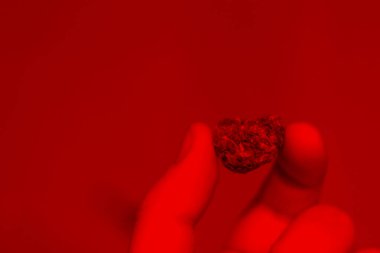 Bulanık bir arka planda kırmızı ışıkta yakın çekim elde az miktarda marihuana. Boşluğu kopyala