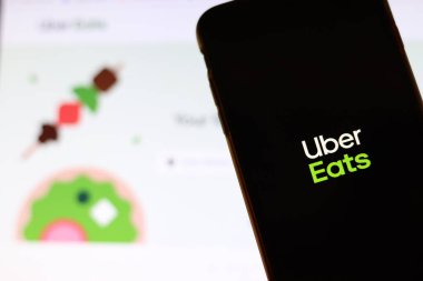 Los Angeles, California, Usa - 21 Kasım 2019: Telefon ekranında Uber Eats logosu ve bulanık arka planda dizüstü bilgisayarda ikon, İllüstrasyon Editörü