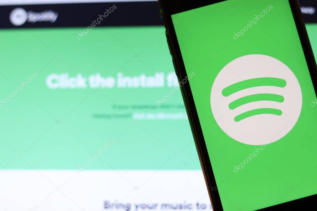 Los Angeles, California, USA - 21 November 2019: Spotify logo on phone screen with icon on laptop on blurry background, Illustrative Editorial.