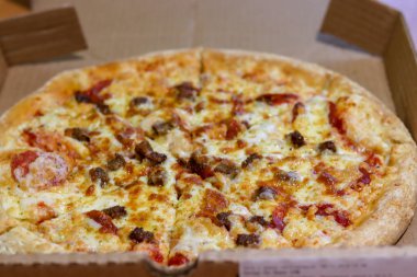 Üstü bol malzemeli pizza. Lezzetli pizza servisi. Masadaki kutuda İtalyan etli pizzası.