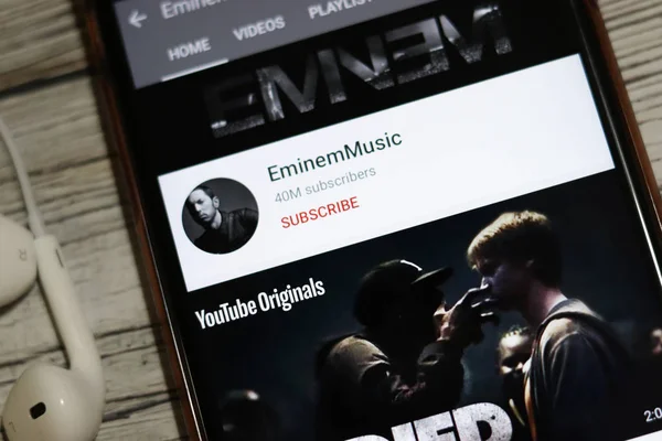 Los Angeles, California, USA - 18 dicembre 2019: icona del canale YouTube di Eminem Music sullo schermo del telefono con auricolari, Editoriale Illustrativo — Foto Stock