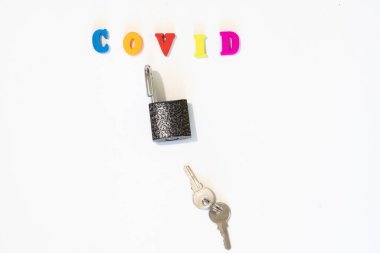 Anahtarları beyaz arkaplanda olan asma kilidi aç. Ülke Sınırı Açılış Konsepti. Covid kelimesi mektup panosundan yapılmış. Coronavirus, Çin kökenli bir salgın virüsüdür..
