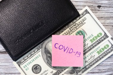 Coronavirus iş ve finans konularına düşkündür. Sözcük Covid-19 kağıt üzerine pasaport ve 100 dolarlık banknotla düz bir görünüm..