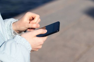 Kadın eller, fotokopi alanı olan bir telefonu caddeye yakın çekimde tutuyor..