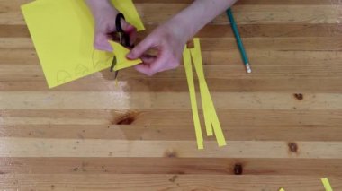 Kadın eli, makasla çocuk oyuncakları için kağıt figürler kesiyor.