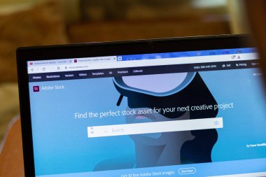 New York, ABD - 9 Nisan 2020: Adobe Stock web sitesi dizüstü bilgisayarı kapat. Ekranda servis kullanan adam, bulanık arkaplan, İllüstrasyon Editörü.