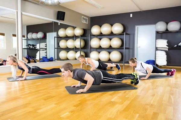 Amigos realizando flexiones en la estera en el gimnasio — Foto de Stock