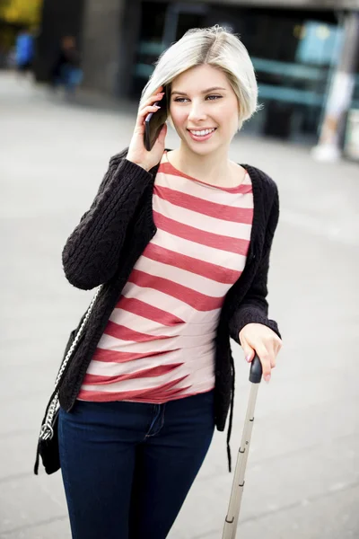 Uśmiechnięta kobieta rozmawia inteligentny telefon poza stacja kolejowa — Zdjęcie stockowe