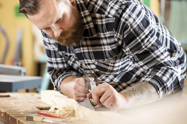 Werk met vliegtuig op houten plank in werkplaats timmerman — Stockfoto