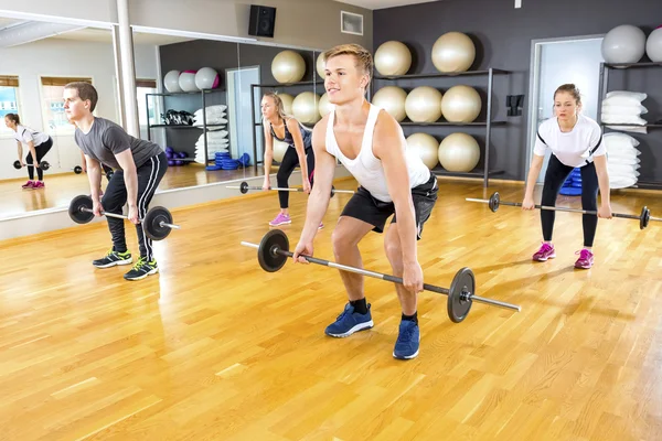 Vänner tränar marklyft med skivstång vikter i gymmet — Stockfoto