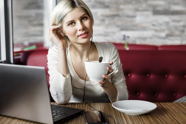 Mujer joven con taza de café y portátil en el café — Foto de Stock