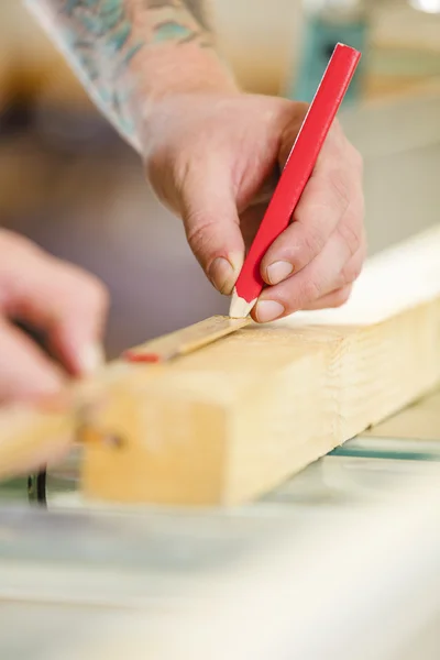 Carpintero mide la longitud de una tabla de madera antes de aserrar — Foto de Stock