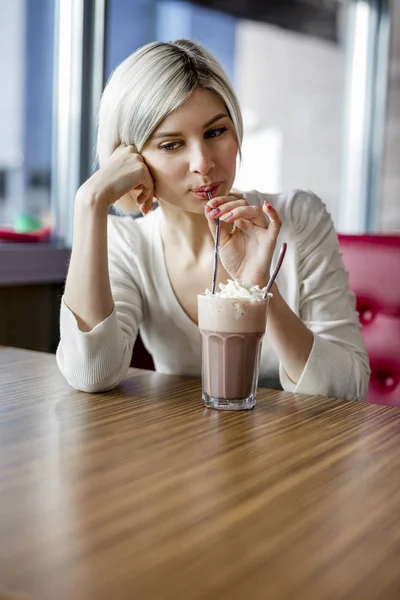 Mulher bonita bebendo chocolate quente com creme no café — Fotografia de Stock