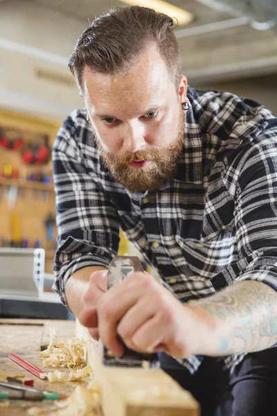 Werk met vliegtuig op houten plank in werkplaats timmerman — Stockfoto