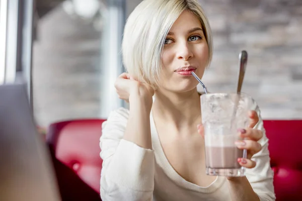 Jovem mulher bebendo chocolate quente no café — Fotografia de Stock