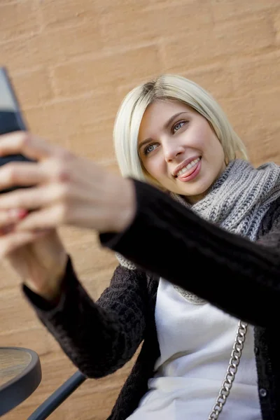 Kvinna att göra ansikten medan du tar Selfie på utomhus Cafe — Stockfoto