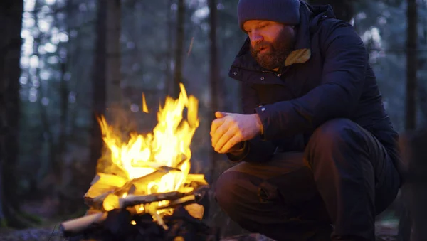 Člověka hřeje sám u táborového ohně v lese — Stock fotografie