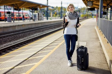 Bagaj ve tren istasyonunda kahve fincanı bekleyen kadın ile