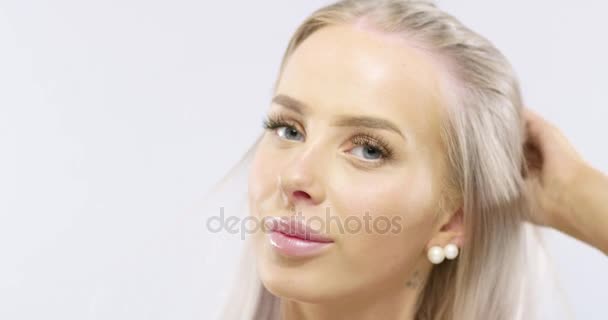 Close-up retrato de uma jovem mulher sorridente tocando seu cabelo loiro — Vídeo de Stock
