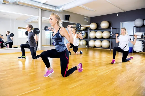 Smiling team do split squats with weights at fitness gym — Stock Photo, Image