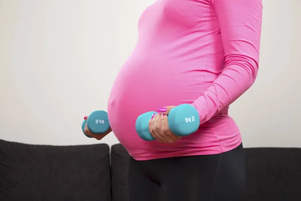 Terhes fiatal nő képzésben súlyokat fedett gyakorlása — Stock Fotó