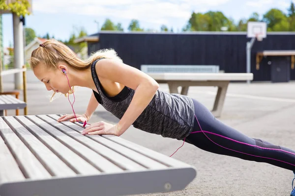 Beslutsam ung kvinna som gör armhävningar på bänk — Stockfoto