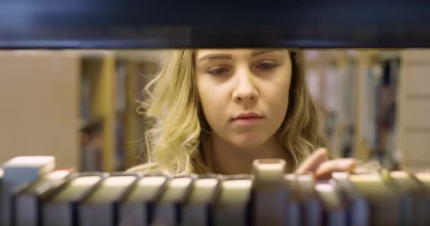 Student hledá knihu v knihovně zaměřená — Stock video