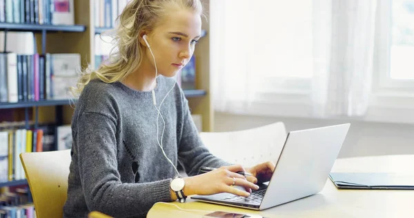 Fleißige Studentin arbeitet in der Bibliothek am Laptop — Stockfoto