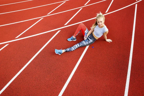 Sporty Woman With Water Bottle Sitting On Running Tracks