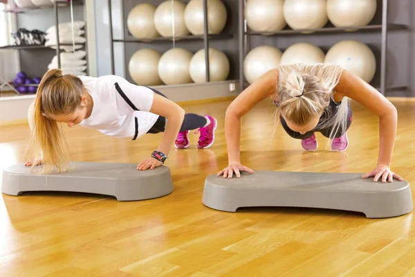 Dos amigas confiadas haciendo flexiones en el gimnasio — Foto de Stock