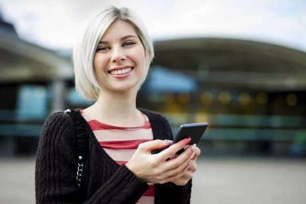 Žena s úsměvem při používání mobilního telefonu mimo železniční stanice — Stock fotografie