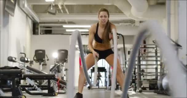Entrenamiento de intervalo de alta intensidad femenino atlético con cuerdas de batalla — Vídeos de Stock