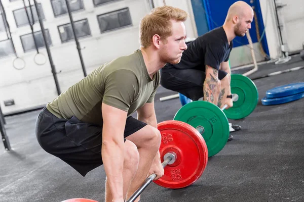 Zwei engagierte Männer trainieren Kreuzheben im Fitnessstudio — Stockfoto