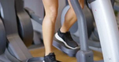 Sportif kadın fitness salonunda elips egzersiz makinede eğitim