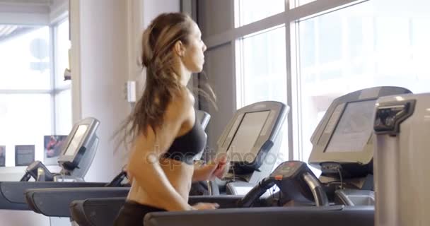 Fit woman in workout clothes running on treadmill machine in fitness gym — Stock Video