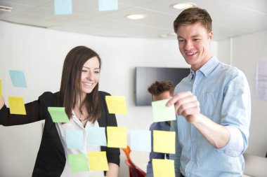 Yöneticiler Office camına yapışmış notlar üzerinde tartışıyor