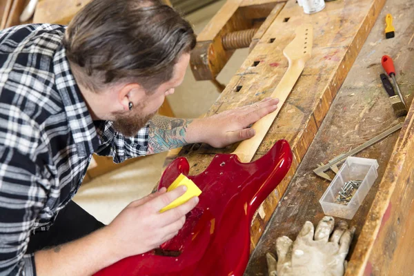 Primer plano del artesano lijando un cuello de guitarra en madera en el taller —  Fotos de Stock