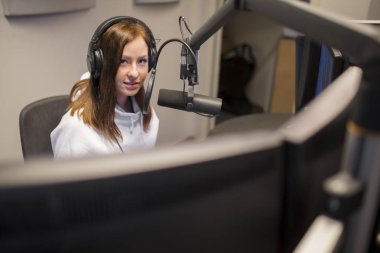 Radyo Studio'da mikrofon kullanırken kulaklık giyen ana bilgisayar