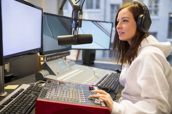 Anfitriã feminina usando painel de controle na estação de rádio — Fotografia de Stock