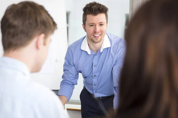 Empresário sorrindo enquanto olha para colegas no escritório — Fotografia de Stock